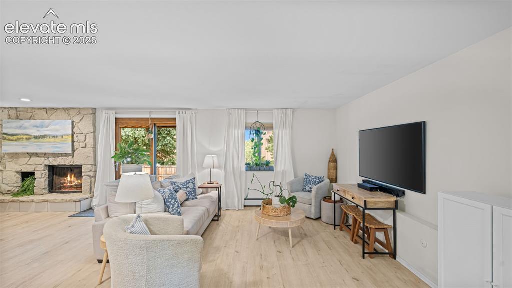 Image 29 of 50: Spacious living area featuring light wood-finish flooring, a stone-clad fir