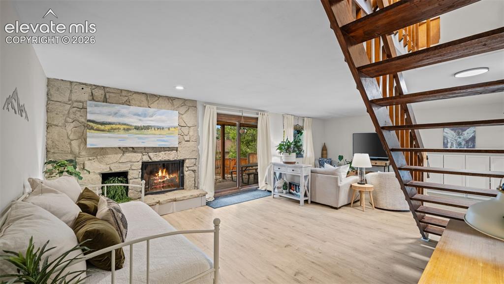 Image 32 of 50: Living area featuring a stone fireplace with hearth, light wood-finish floo
