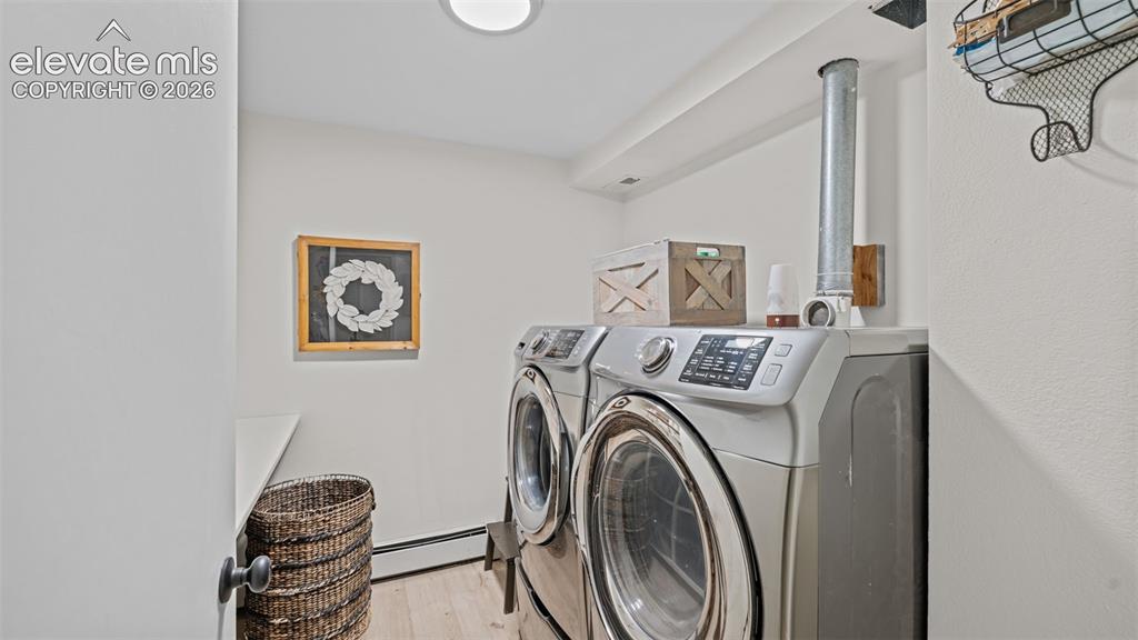 Image 33 of 50: Dedicated laundry area featuring front-loading appliances, light wood-finis
