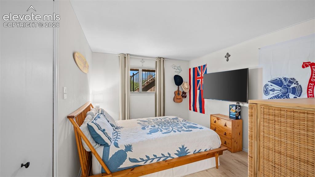 Image 34 of 50: Bright bedroom featuring light-toned wood-finish flooring, a window with ex