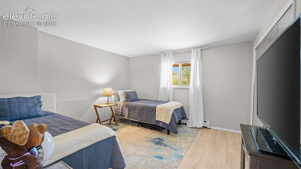 Image 37 of 50: Bedroom featuring light-toned walls and wood-finish flooring