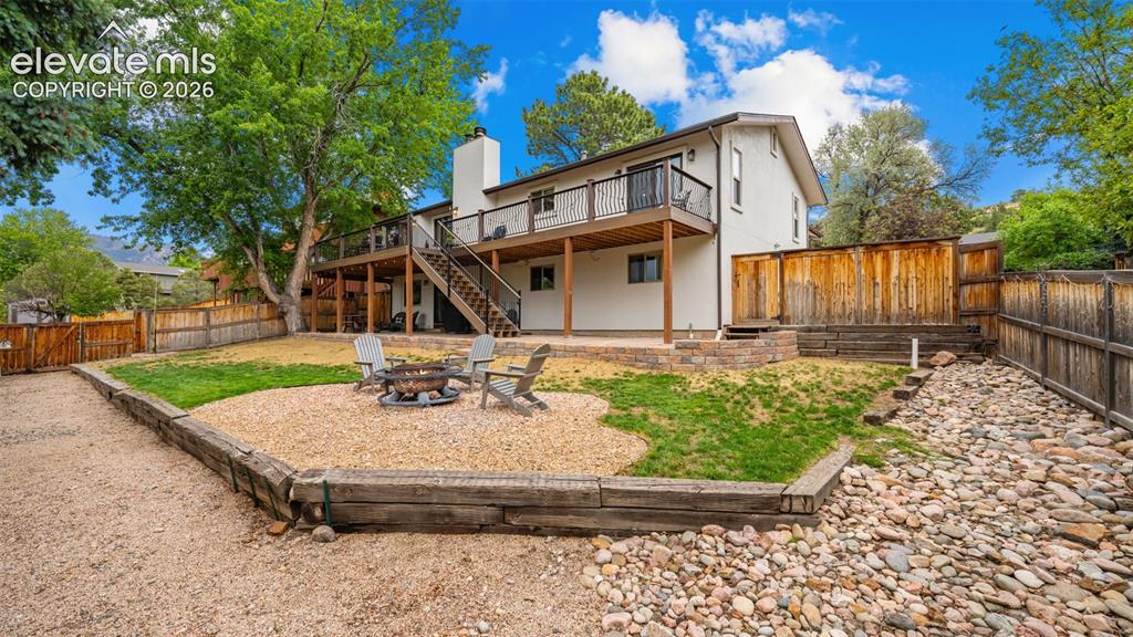 Image 38 of 50: Expansive backyard featuring a multi-level deck, a gravel fire pit area, a 