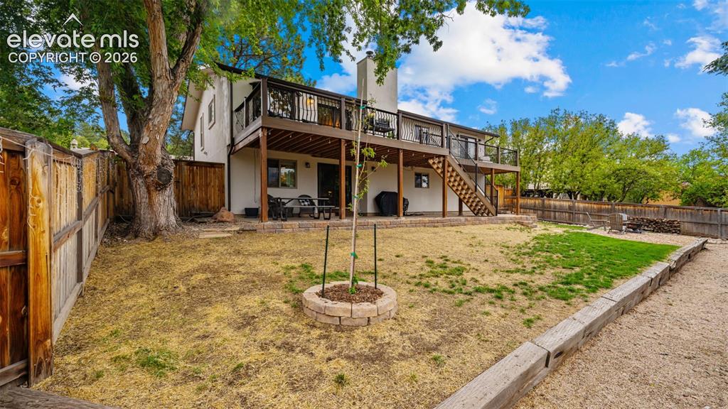 Image 39 of 50: Spacious backyard with a two-story deck, exterior stairs, and a ground-leve