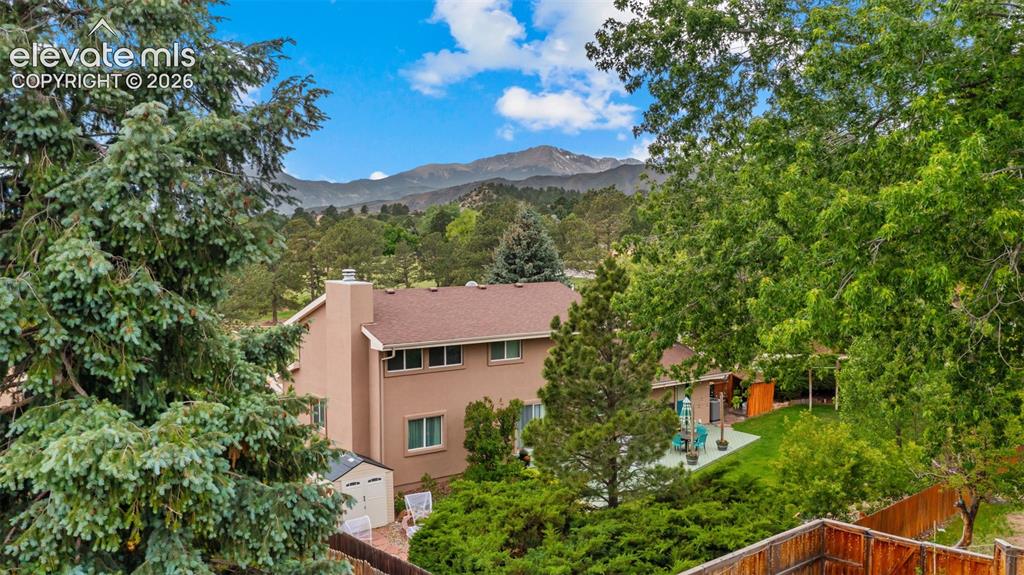 Image 47 of 50: Expansive backyard featuring a manicured lawn, established trees, and a con
