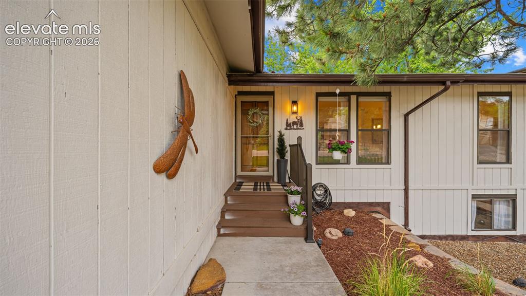 Image 6 of 50: Inviting front entry featuring a multi-pane glass door, exterior wall light