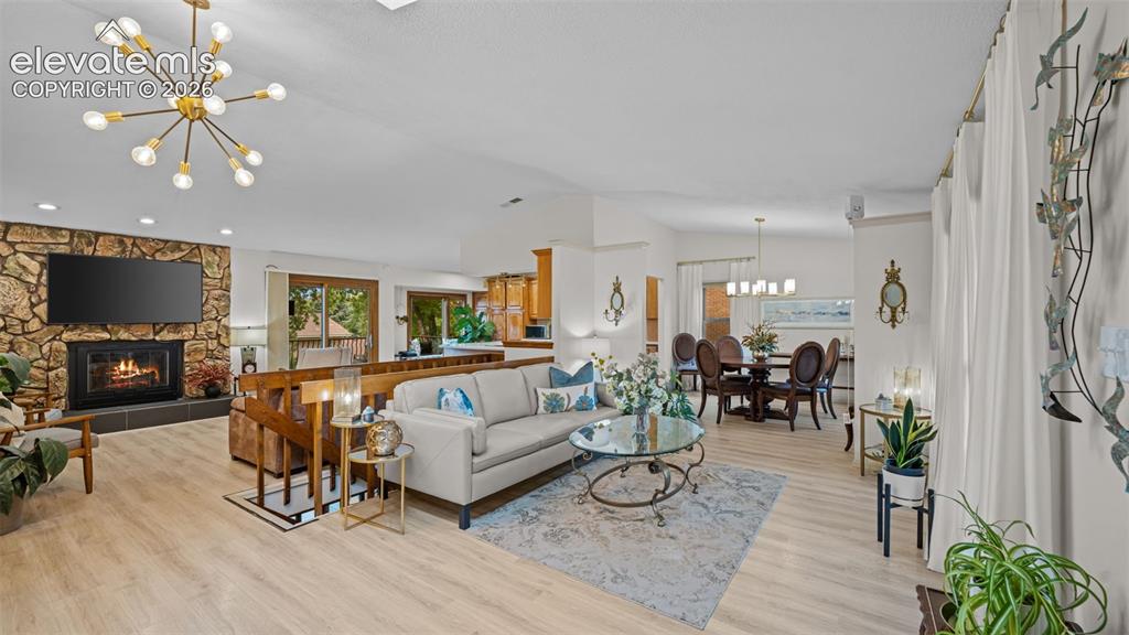 Image 7 of 50: Spacious living area featuring light wood-finish flooring, a stone-clad fir