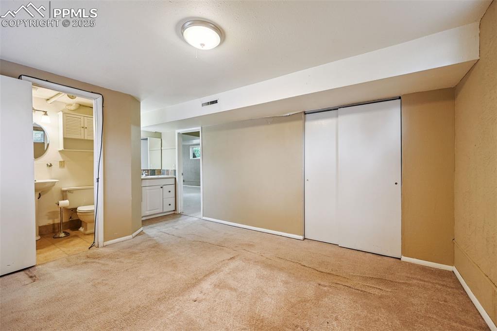 Image 17 of 44: Unfurnished bedroom featuring light carpet, connected bathroom, and a close
