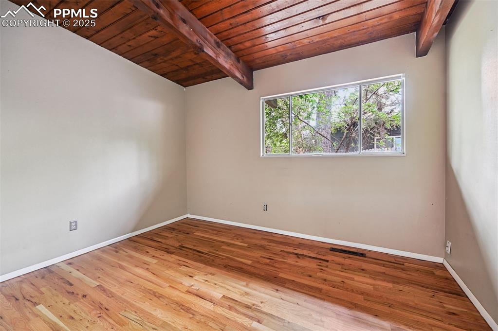 Image 28 of 44: Empty room with wooden ceiling and wood finished floors