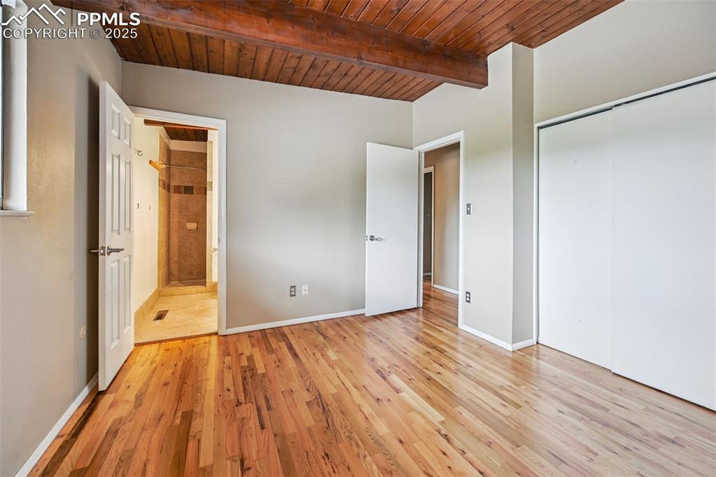 Image 30 of 44: Unfurnished bedroom with a wooden ceiling with exposed beams, light wood-st