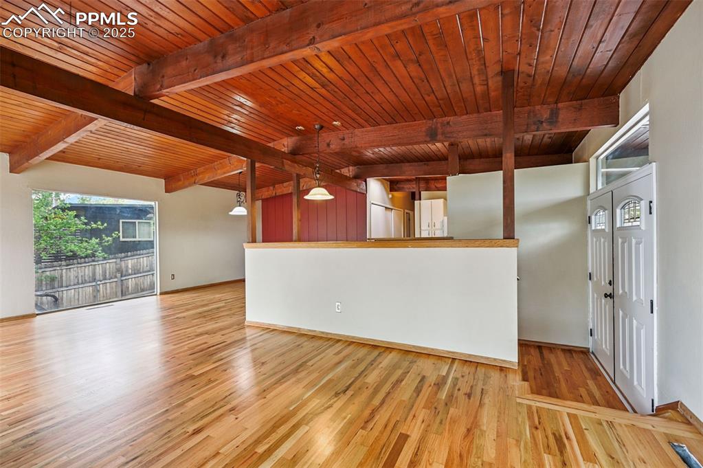Image 6 of 44: Unfurnished living room featuring a wooden ceiling with exposed beams and w