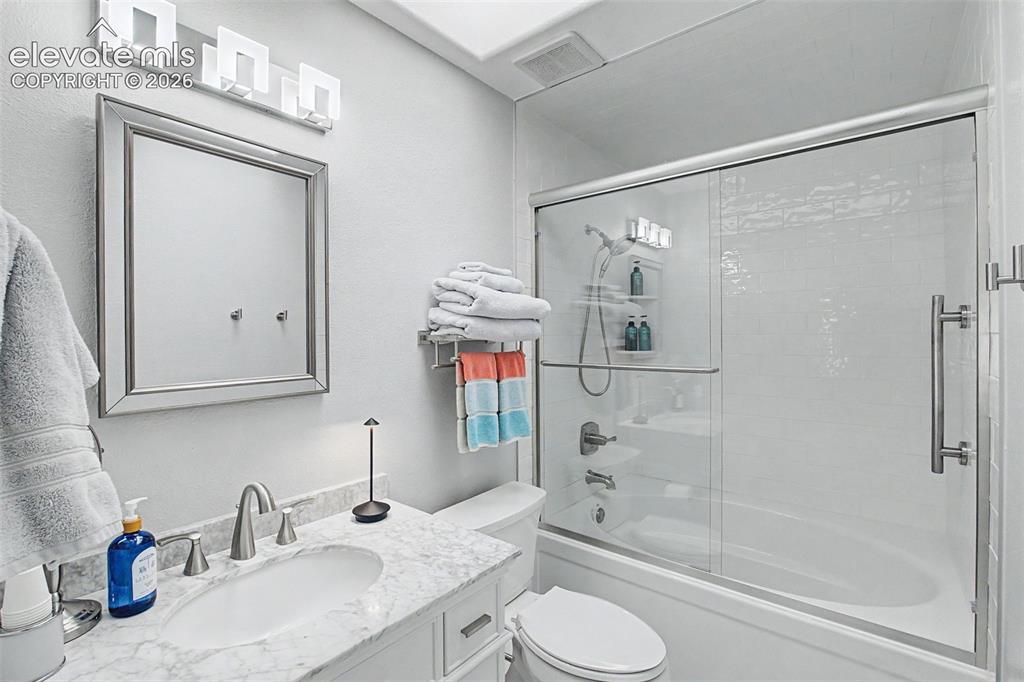Image 15 of 36: Beautifully remodeled ensuite bath features a skylight and stone countertop
