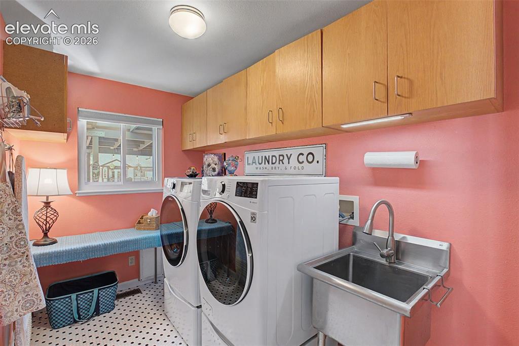 Image 18 of 36: Spacious laundry room featuring built-in storage, utility sink, and a windo