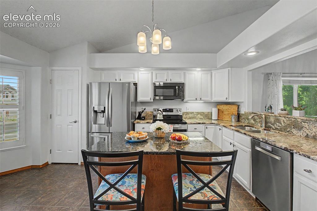 Image 6 of 36: The upgraded kitchen features granite countertops, an island with breakfast