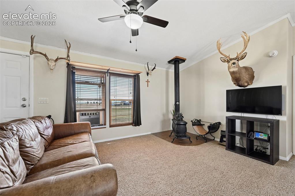 Image 13 of 36: Living area with carpet flooring, a ceiling fan with integrated lighting, a