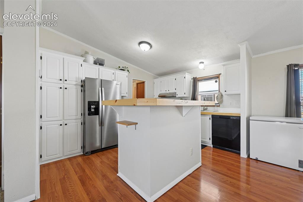 Image 14 of 36: Kitchen featuring wood-finish flooring, white cabinetry, a central island w