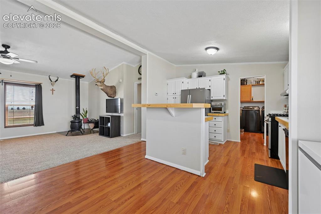 Image 15 of 36: Kitchen featuring white cabinetry, light wood-finish countertops, stainless