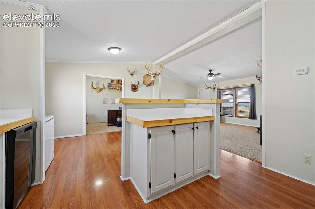 Image 16 of 36: Kitchen area featuring wood-finish flooring, white cabinetry with black har