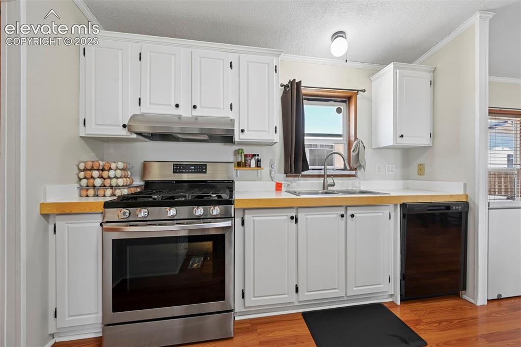 Image 18 of 36: Kitchen featuring white cabinetry, light wood-finish countertops, stainless