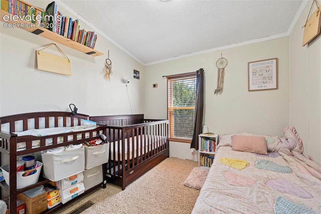 Image 19 of 36: Carpeted room with a single window featuring blinds, a built-in wood shelf,