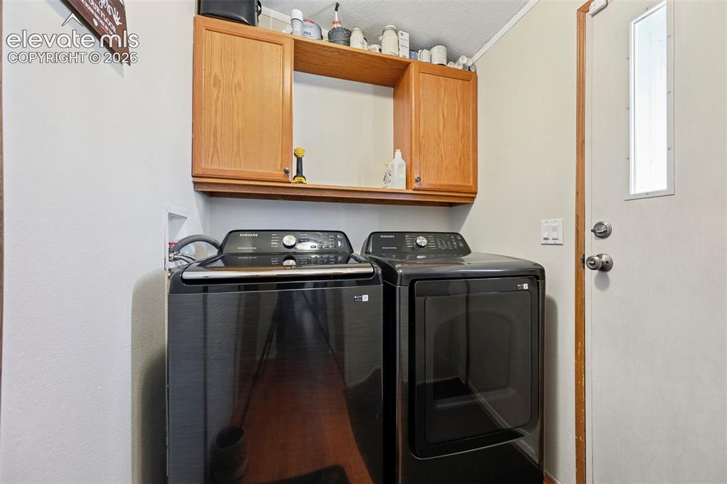 Image 23 of 36: Laundry area featuring wood-finish cabinetry, open shelving, and a white ex