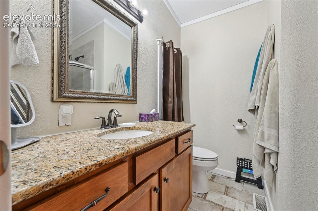 Image 28 of 36: Vanity featuring an undermount sink, granite countertop, and wood cabinetry
