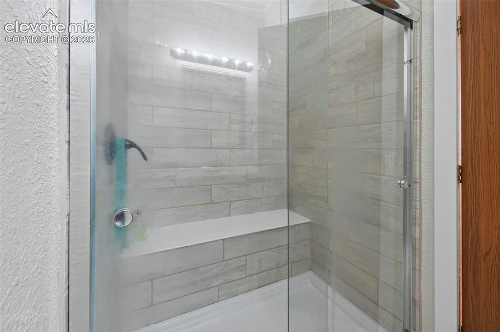 Image 29 of 36: Glass-enclosed shower featuring light-toned rectangular wall tiling, an int