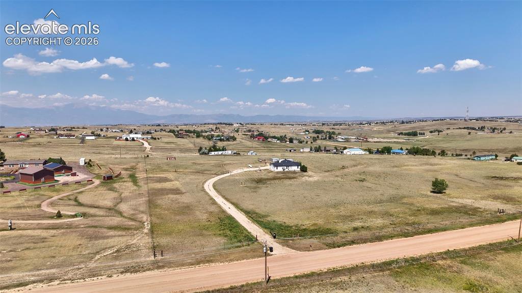 Image 32 of 36: Expansive rural property featuring a winding dirt road, scattered residenti