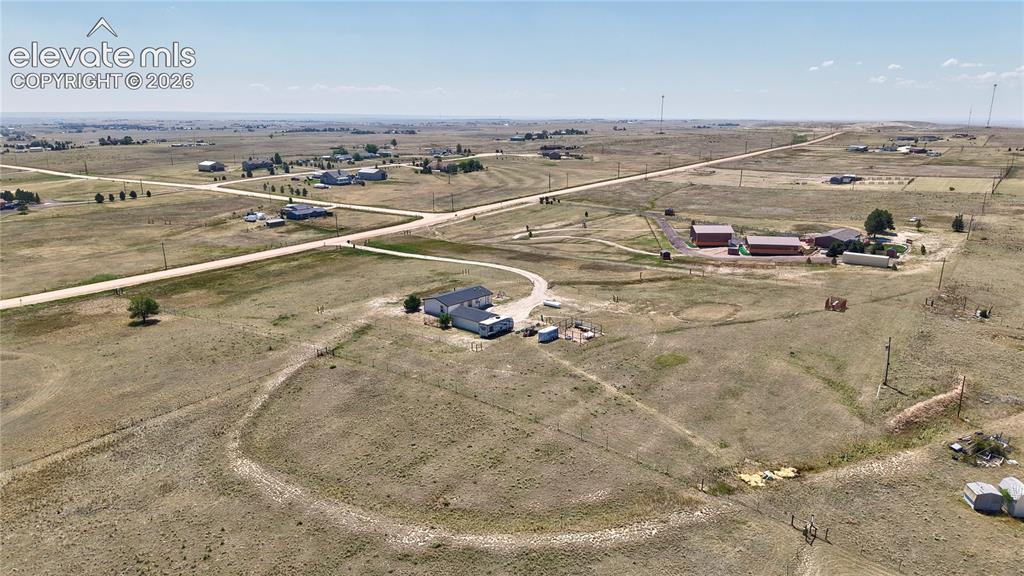 Image 5 of 36: Expansive open land featuring multiple residences, outbuildings, and unpave