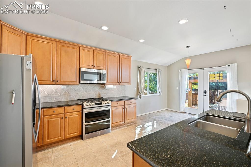 Image 4 of 30: Kitchen featuring stainless steel appliances, gas range, dark stone counter