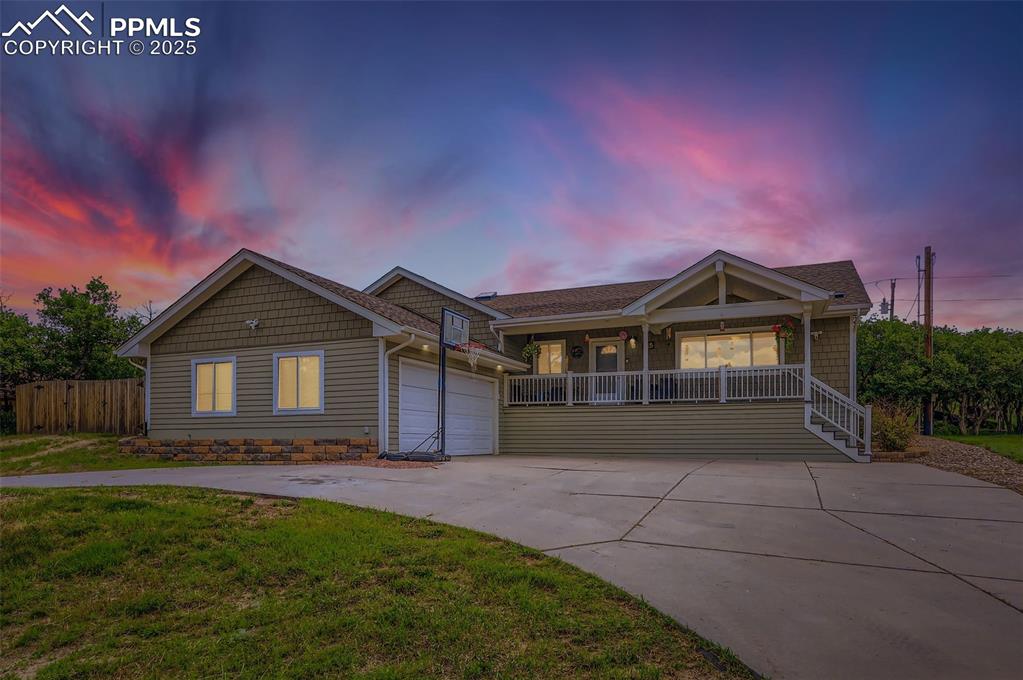 Caption: Ranch-style home featuring driveway, covered porch, and a garage