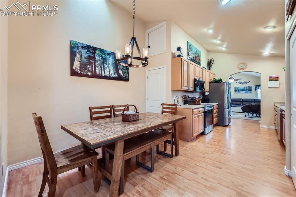Image 12 of 29: Dining room featuring light wood-style flooring, arched walkways, and a cha