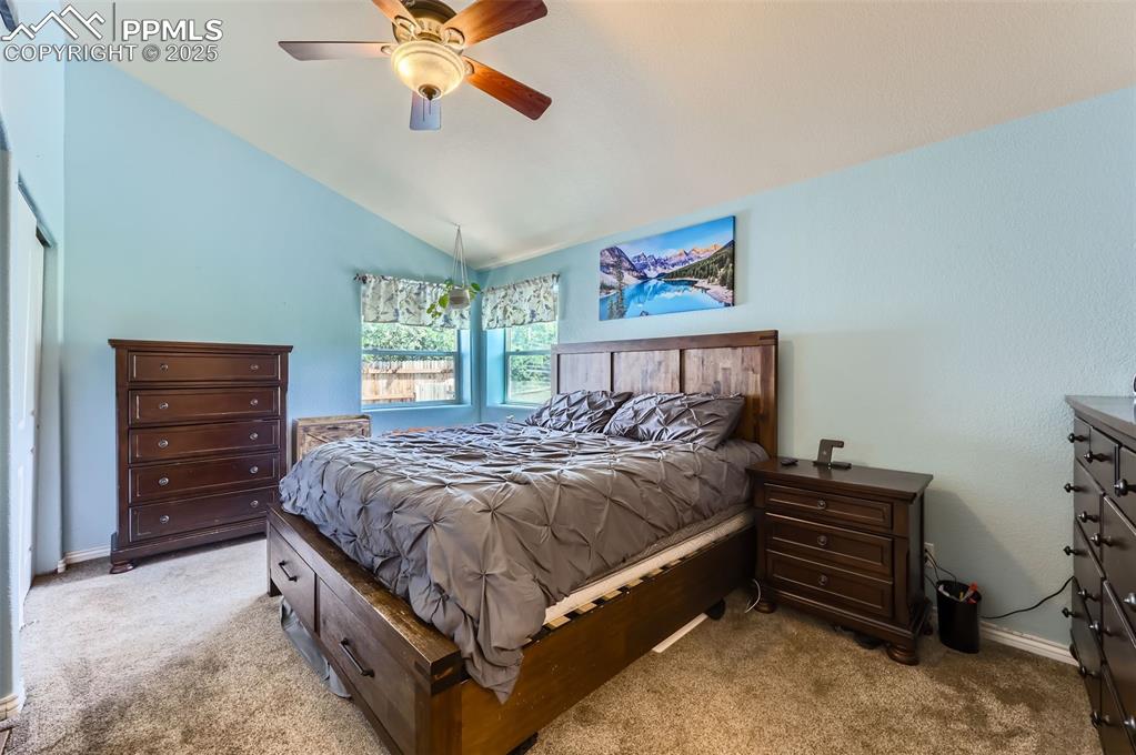 Image 13 of 29: Bedroom with light colored carpet, vaulted ceiling, and a ceiling fan