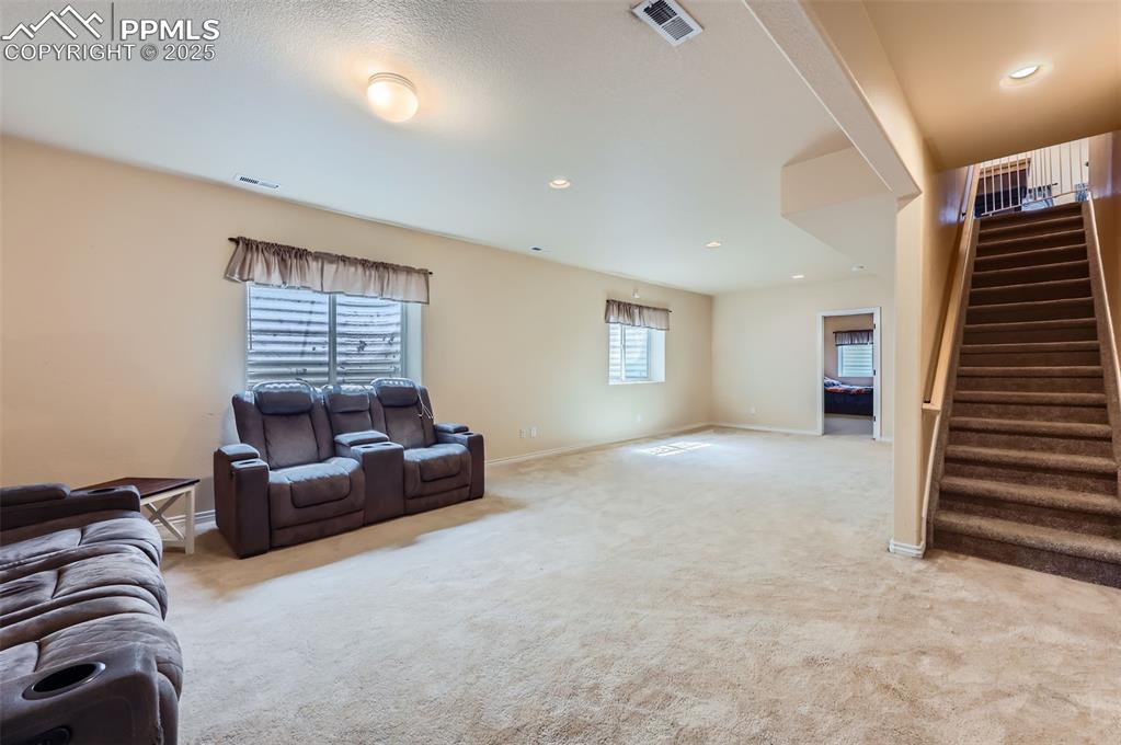 Image 22 of 29: Living room with light carpet, recessed lighting, and stairs