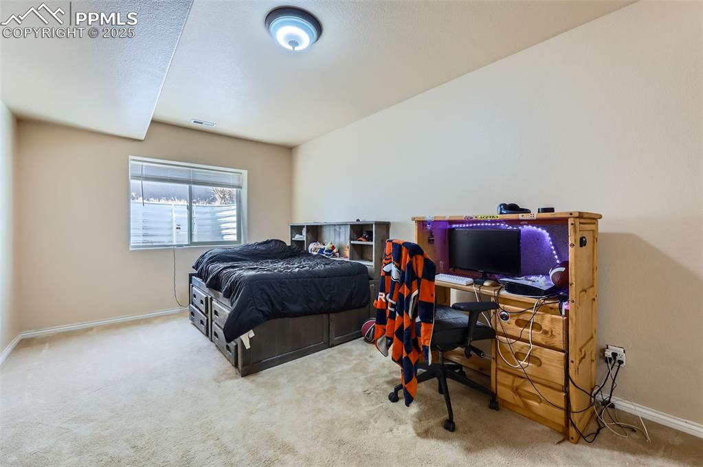 Image 28 of 29: Carpeted bedroom featuring baseboards and an office area