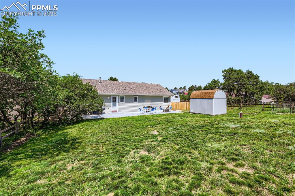 Image 5 of 29: Rear view of house featuring a patio area, a shed, and a fenced backyard