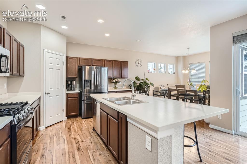 Image 11 of 28: Kitchen featuring wood-finish flooring, dark wood cabinetry, stainless stee