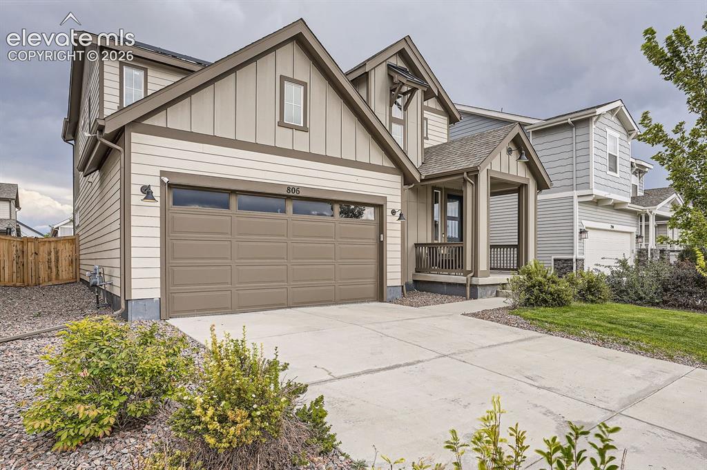 Image 2 of 28: Two-story residence featuring light-toned siding, a two-car garage with a p