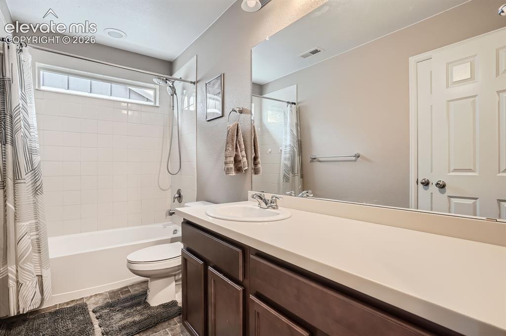 Image 24 of 28: Laundry area featuring front-loading machines, built-in shelving, tiled flo