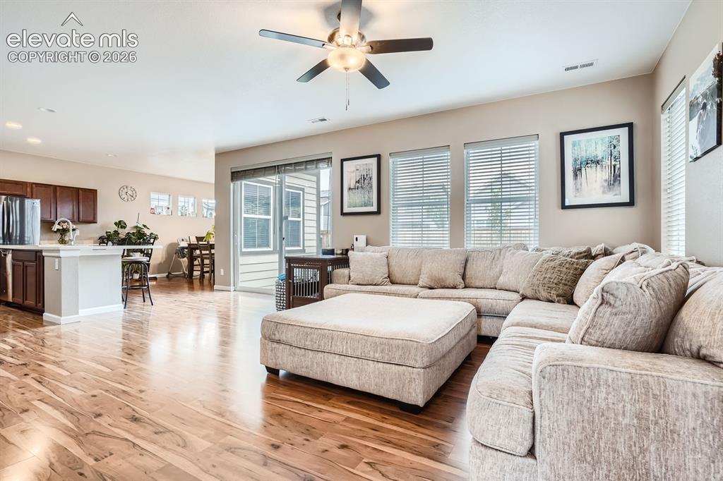 Image 6 of 28: Open-concept living area featuring wood-finish flooring, a ceiling fan with