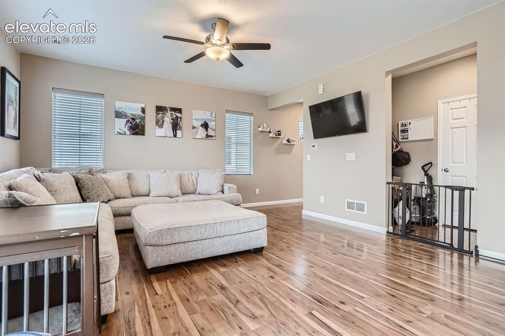 Image 7 of 28: Spacious living area featuring wood-finish flooring, neutral wall tones, an