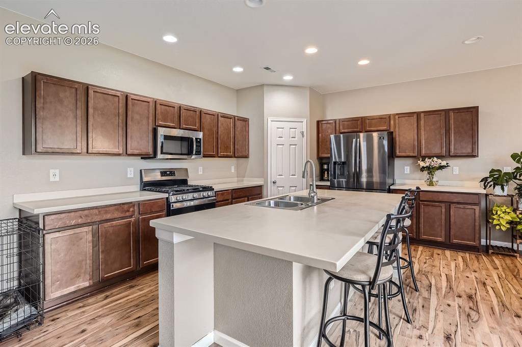 Image 9 of 28: Open-concept kitchen featuring an island with an integrated double sink, st