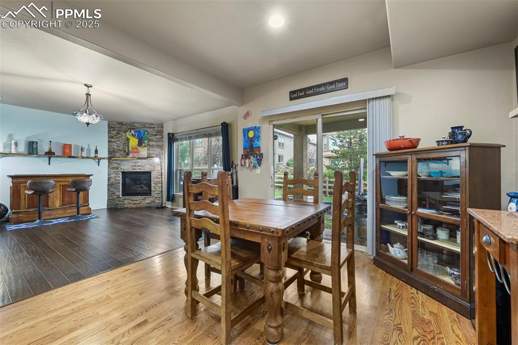 Image 13 of 50: Dining room with wood finished floors, a fireplace, and beam ceiling