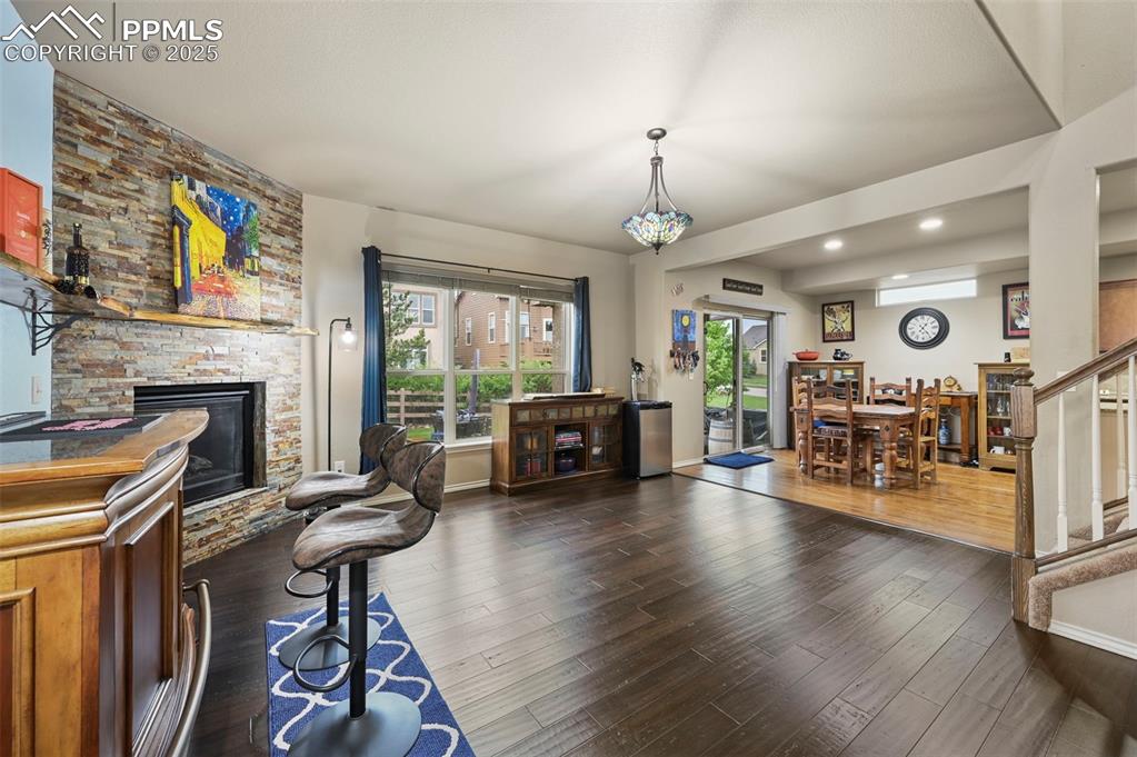 Image 17 of 50: Living room featuring a stone fireplace, stairs, wood finished floors, and 