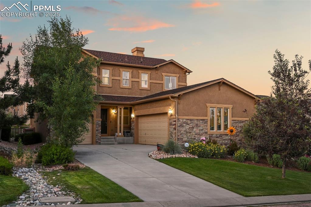 Image 2 of 50: View of front of house featuring stucco siding, driveway, a chimney, a yard