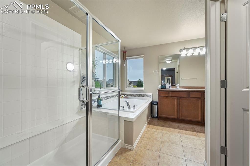 Image 21 of 50: Bathroom with vanity, a garden tub, a stall shower, and tile patterned floo