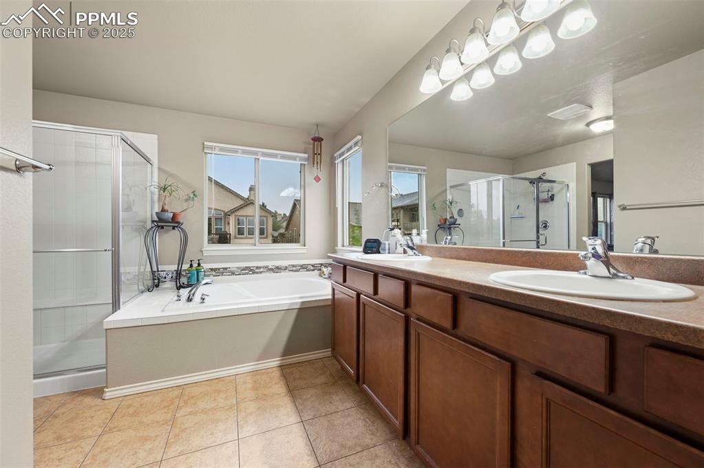 Image 22 of 50: Full bathroom featuring a stall shower, double vanity, a bath, and tile pat