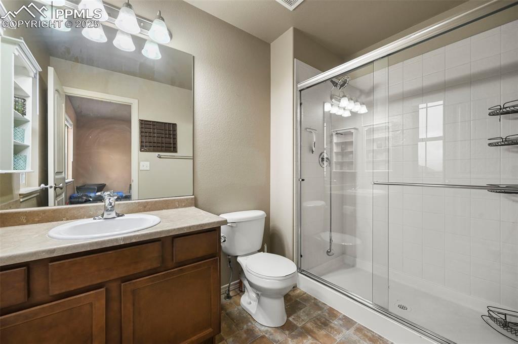 Image 28 of 50: Full bath with a stall shower, vanity, and stone finish flooring