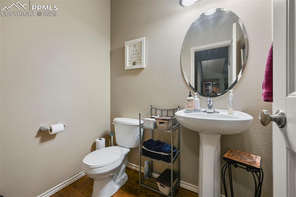 Image 30 of 50: Half bathroom with toilet and wood finished floors