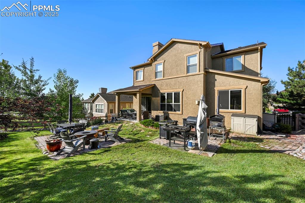 Image 37 of 50: Back of property with a patio, stucco siding, a chimney, and a yard