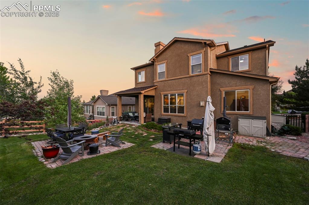 Image 48 of 50: Back of property at dusk with an outdoor fire pit, a patio area, a chimney,